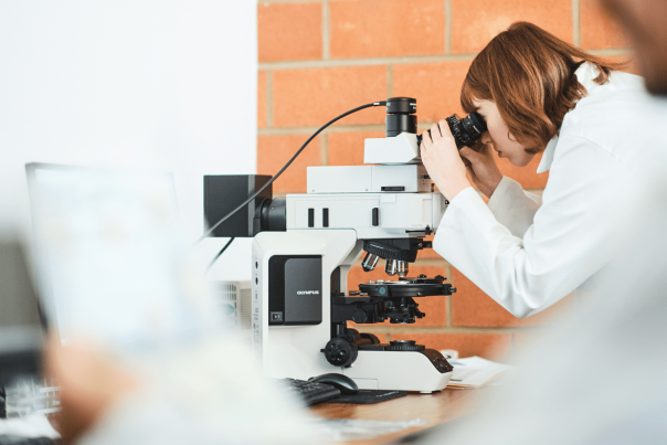 Une chercheurse observant au travers d'un microscope