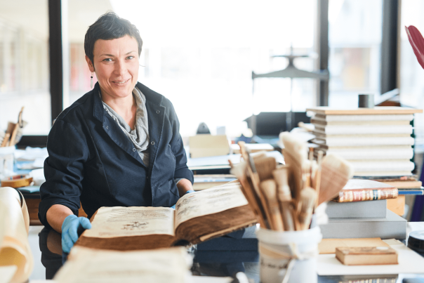 Une chercheuse qui consulte un ouvrage précieux