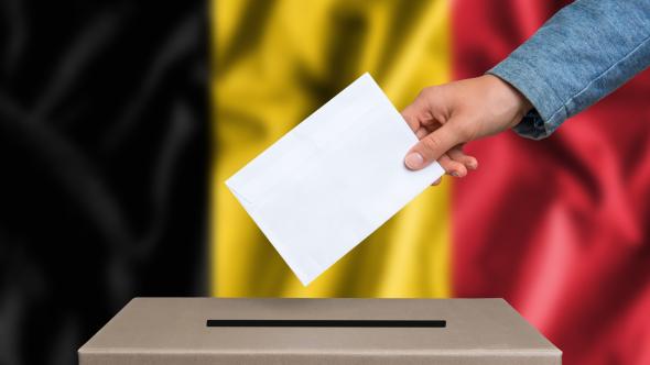 shutterstock_487377016-main qui glisse un billet dans une urne avec un drapeau belge en fond d'image