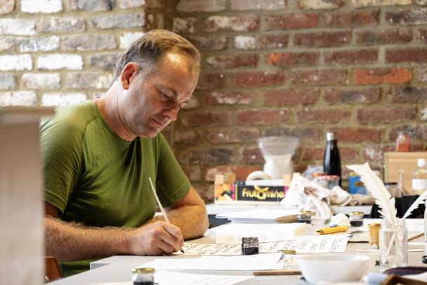 Participant qui écrit sur un parchemin - Colloque-atelier parchemins et enluminures UNamur (2024)