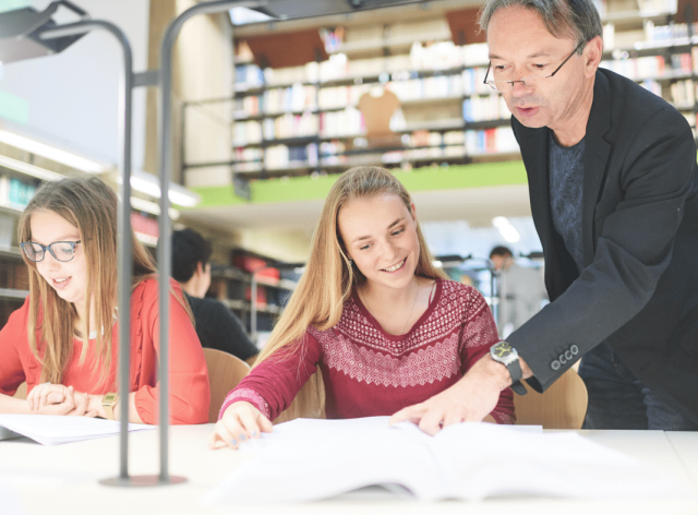 Un professeur avec des étudiantes à la bibliothèque