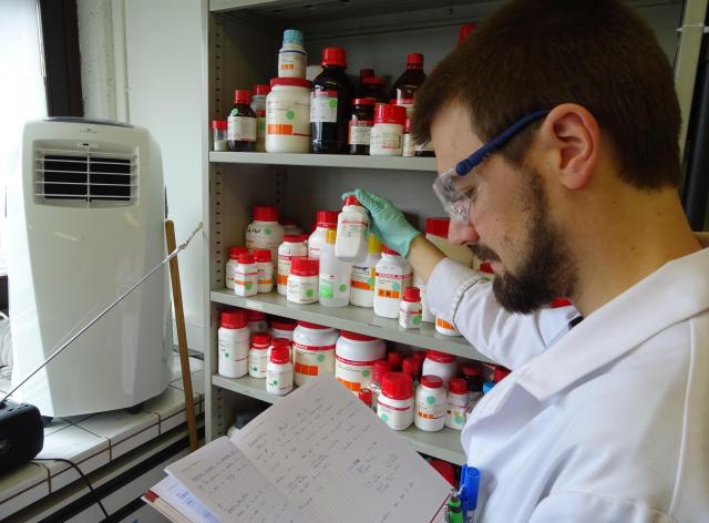 Un chimiste devant une armoire contenant des produits chimiques