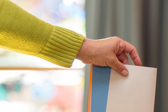 Personne tenant un bulletin de vote au dessus d'un urne